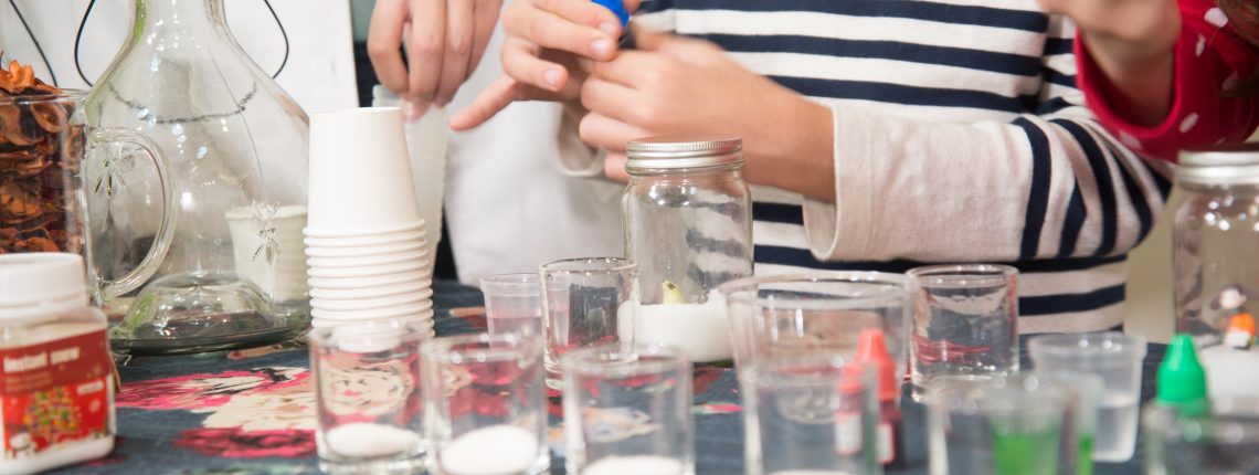 teacher and students with jars on a table