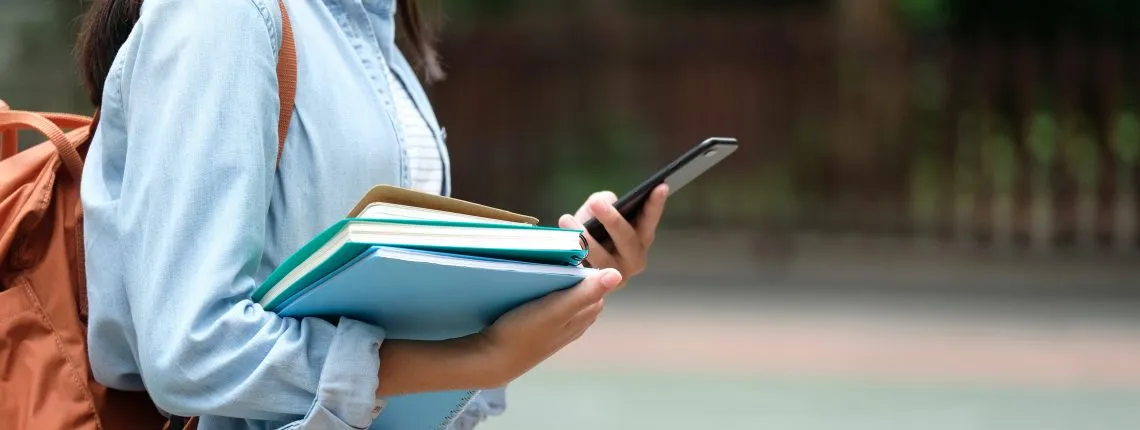 teenager holding books and phone
