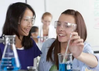 Female high school students performing experiment in chemistry lab