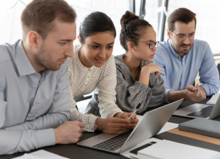 People leaning over their computers talking