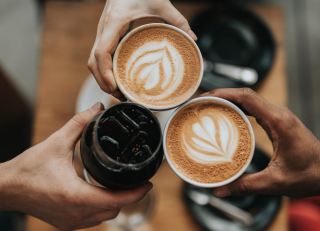 Three hands holding cups of coffee