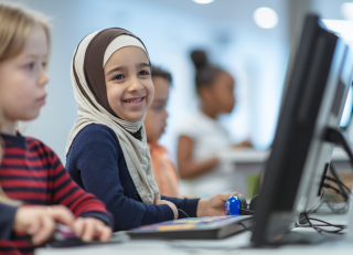 Student sitting at a computer smiling