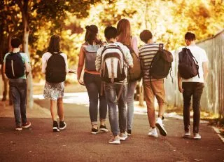 Back of students walking with backpacks on