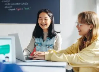 Two girls coding on a computer